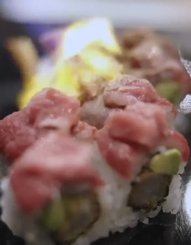 Sushi gourmet con capas de pescado fresco y vegetales, presentado en un plato elegante. Ideal para amantes de la cocina japonesa.